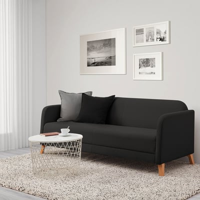 Modern minimalist living room with black LINANÄS sofa, white side table, and black-and-white decor.