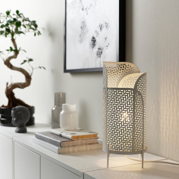 Cylindrical LUNNOM lamp with patterns emissions warm light, books, vases, bonsai.