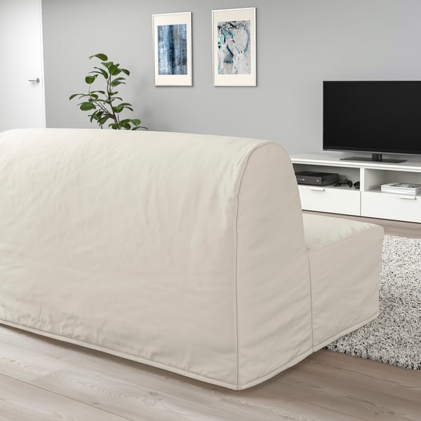 Modern living room with beige sofa-bed, tv unit, rug, plant, grey wall art.