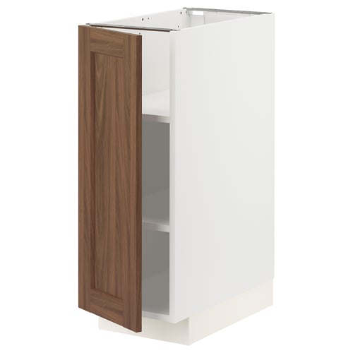 A white METOD kitchen cabinet with a single walnut-colored door partially open, revealing an adjustable shelf inside.