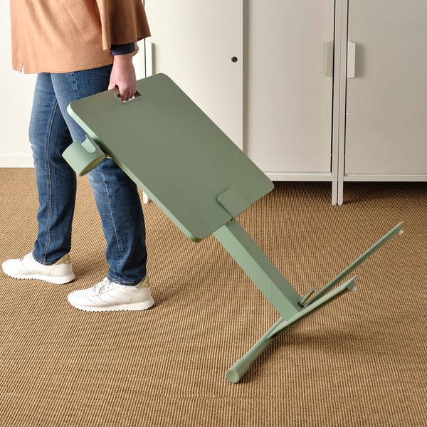 Person adjusting height of green MITTZON laptop table with a gas spring mechanism.