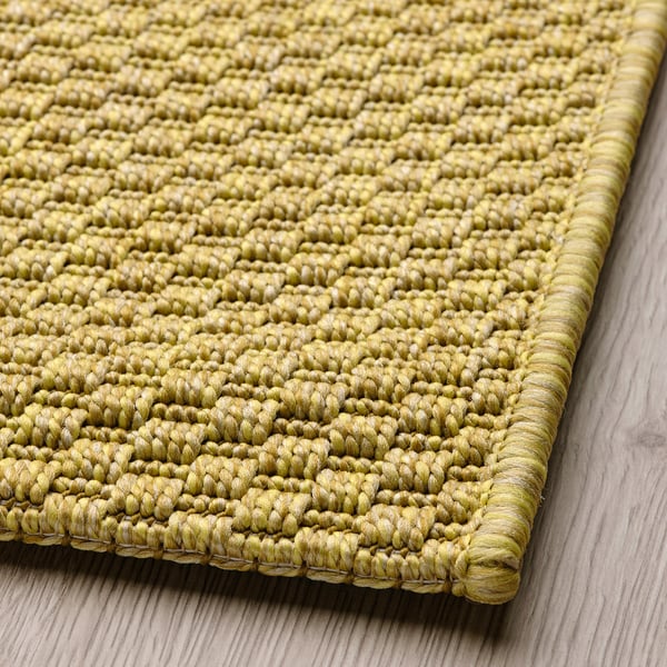 Green woven rug laid on wooden floor, showcasing quality texture and craftsmanship.