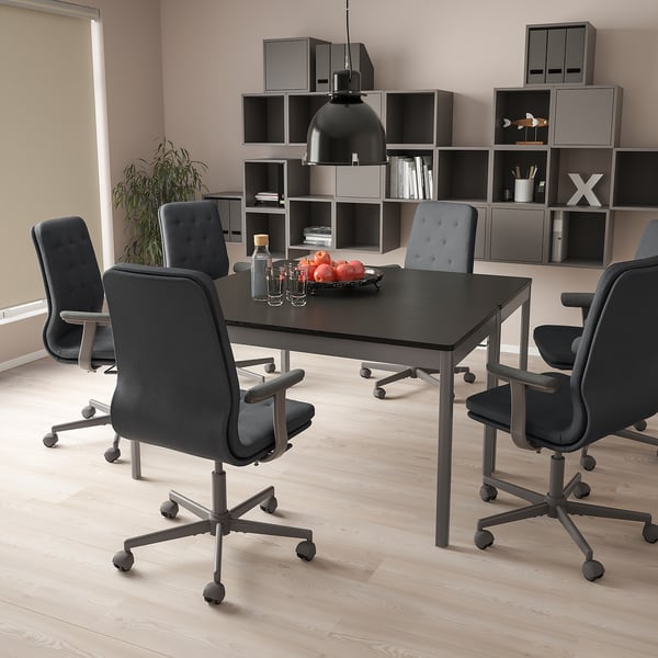 Modern minimalist workspace with black table, 6 grey MULLFJÄLLET chairs, light floor, grey bookshelf.