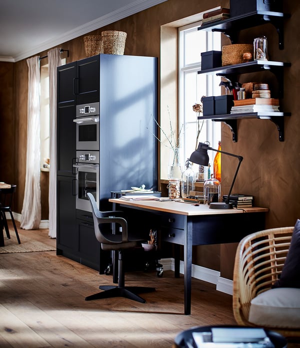 Home office scene with black ODGER chair, desk, shelves, and window.