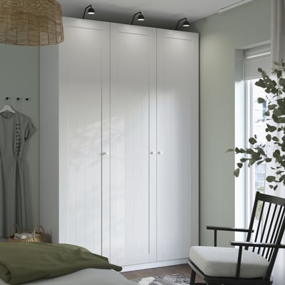 Modern bedroom with large white PAX wardrobe, sleek design, light wood floor, green accents, and window.