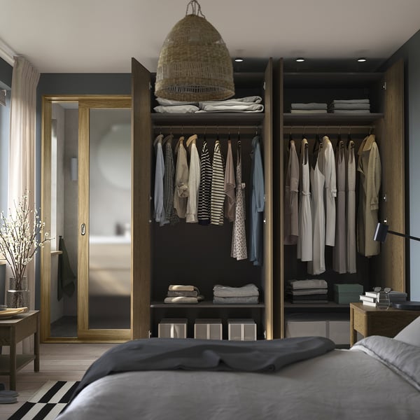 Open wardrobe with clothes & boxes; grey bed, pendant lamp