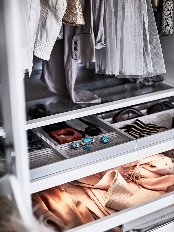 Organised closet with hanging clothes and drawers. Upper drawers contain jewellery and small items, lower drawer holds folded silk clothes.