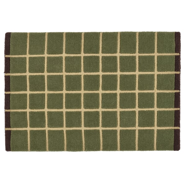 A square POSTKONTOR door mat featuring a green and beige chequered pattern. Its made from wool with eva plastic backing for stability and durability.