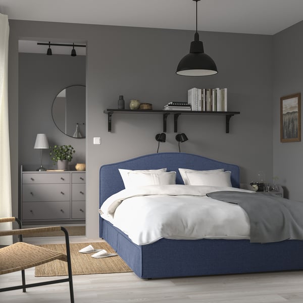 Grey bedroom with blue bed, grey walls, bookshelves, dresser & mirror.
