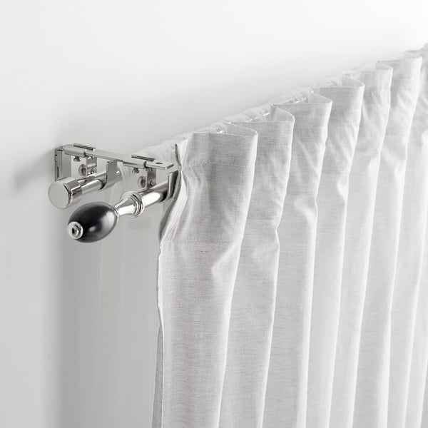 Curtain rod bracket holding rods together. White curtains draped over, displaying connector functionality.