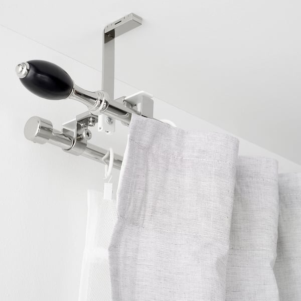 Double curtain rod set mounted near ceiling, featuring black-lacquered aluminium finials and multiple connectors for versatile installation.