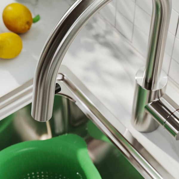 Modern kitchen tap with sleek, curved design and pull-out sprayer, reflecting quality and functionality.