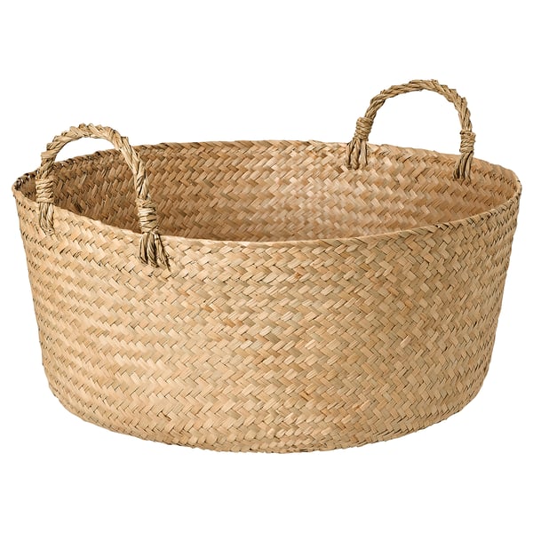 A handmade SANDJORD woven basket. Its beige, circular, and made from sedge material. It two handles for easy carrying.