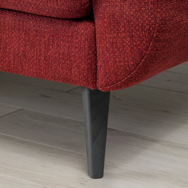 Close-up of a red cushioned sofa with wooden legs, showcasing quality upholstery and sturdy design.