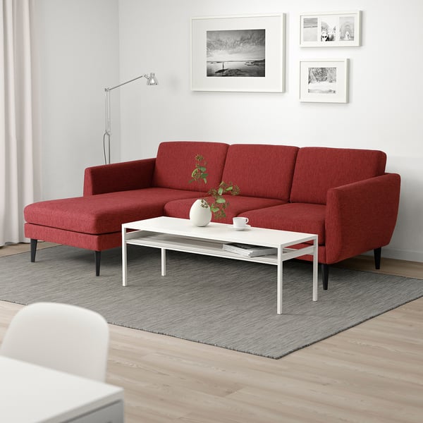 Modern living room: red SMEDSTORP sofa, wooden floor, wall art, white coffee table, rug, plant, lamp.