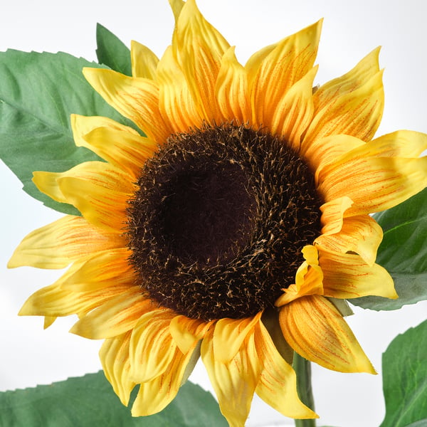 Bright yellow sunflower with green leaves, meticulously crafted to resemble real petals and stem, exuding lifelike quality.
