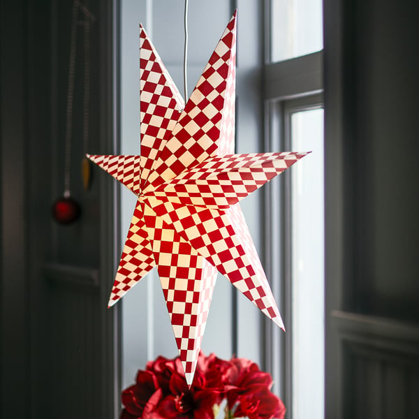 STRÅLA red & white star-shaped lamp shade, hanging outside door, slightly larger than nearby flower arrangement.