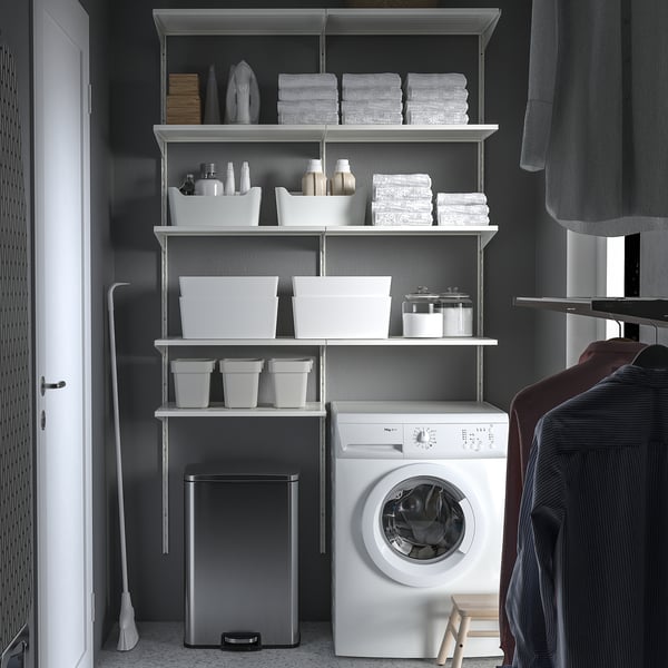 Organised closet SULTEN stainless steel pedal bin next to a white washing machine, surrounded by neatly arranged shelves with laundry items.