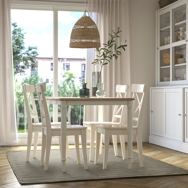 Cosy dining room with TIDTABELL table, grey rug, round table & chairs, pendant light, vases, cabinet, urban view.