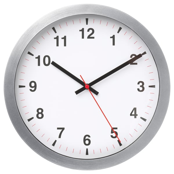 A round, silver-framed wall clock with a white face, black numbers, and hands, indicating the time.