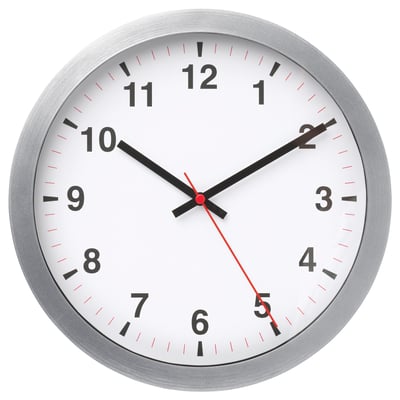 A round, silver-framed wall clock with a white face, black numbers, and hands, indicating the time.