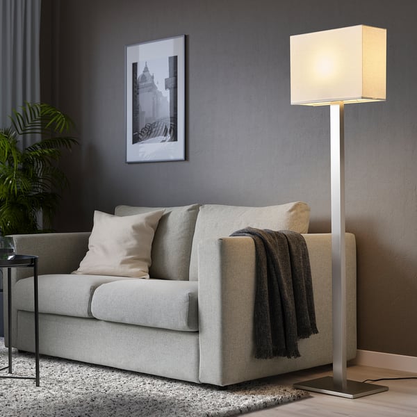 Cosy living room with grey TOMELILLA floor lamp, sofa, throw blanket, pillows, plant, and wall picture.