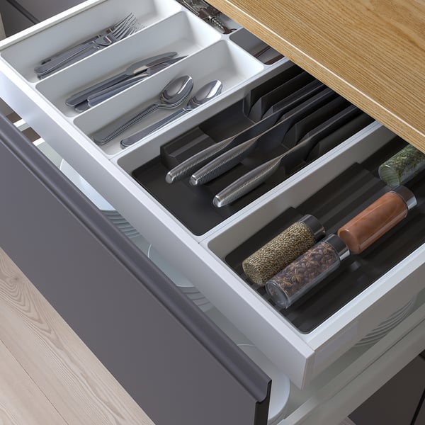 Silverware organiser drawer with cutlery, knives, and spice jars.