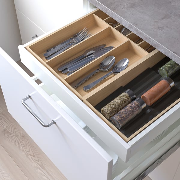 Wooden drawer organiser with metal cutlery and spice jars.