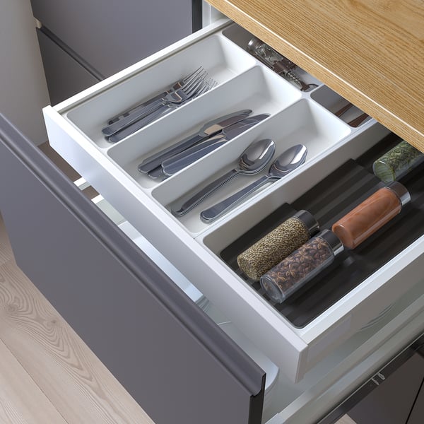Organised kitchen drawer with utensils and spice jars.