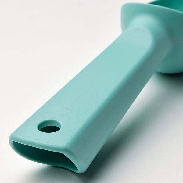Turquoise plastic ice-cream scoop, smooth surface with hole, resting on light blue background.