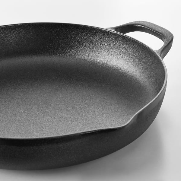 Black cast iron frying pan with two handles on a white background. Smooth, evenly heat-conducting surface, ideal for cooking.