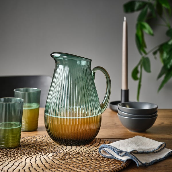 Table setting with VARDAGEN glass pitcher holding liquid, cups, bowls, candle, and napkin.
