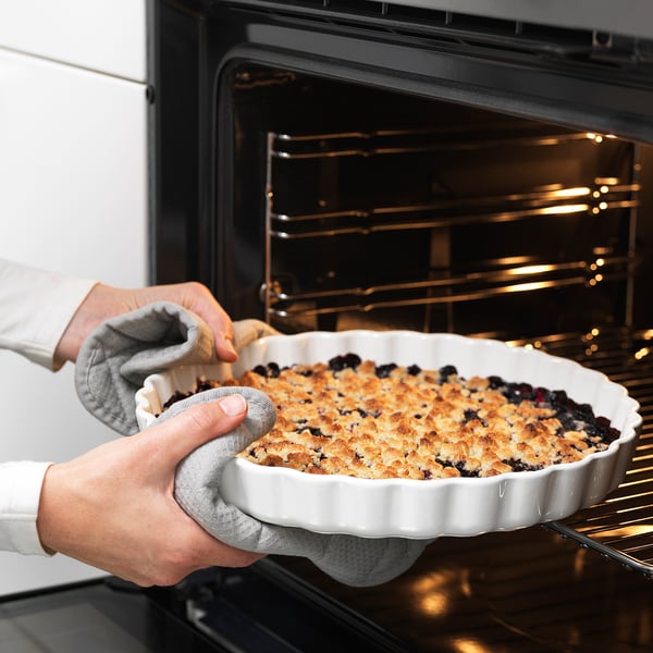 Baker removes pie from oven with mitts.