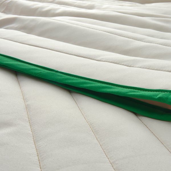 Close-up of stylish VETEJORDFLY bedspread with green edge. Smooth, detailed texture visible.