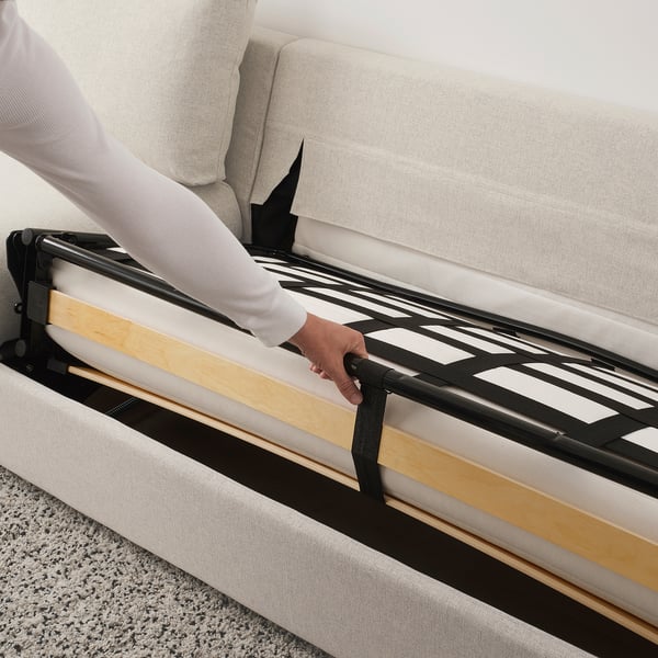 Person adjusting sofa-bed mechanism, preparing for use.