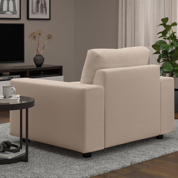 Light living room with beige VIMLE armchair, dark side table, coffee mug, and plant.