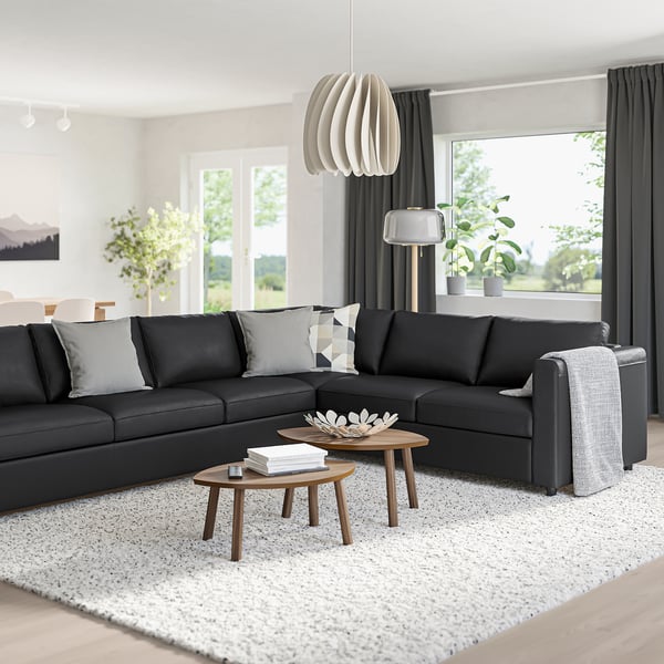 Modern living room with black VIMLE sectional sofa, two coffee tables, and white rug.