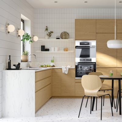Modern kitchen with oak cabinets, marble countertop, stainless steel appliances, and wooden chairs.