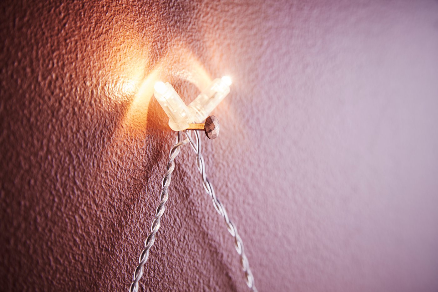 Un gros plan d'un clou dans le mur avec des lumières de fée attachées