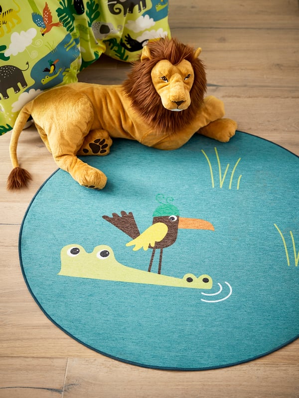 Un león de peluche sobre un tapete infantil IKEA.