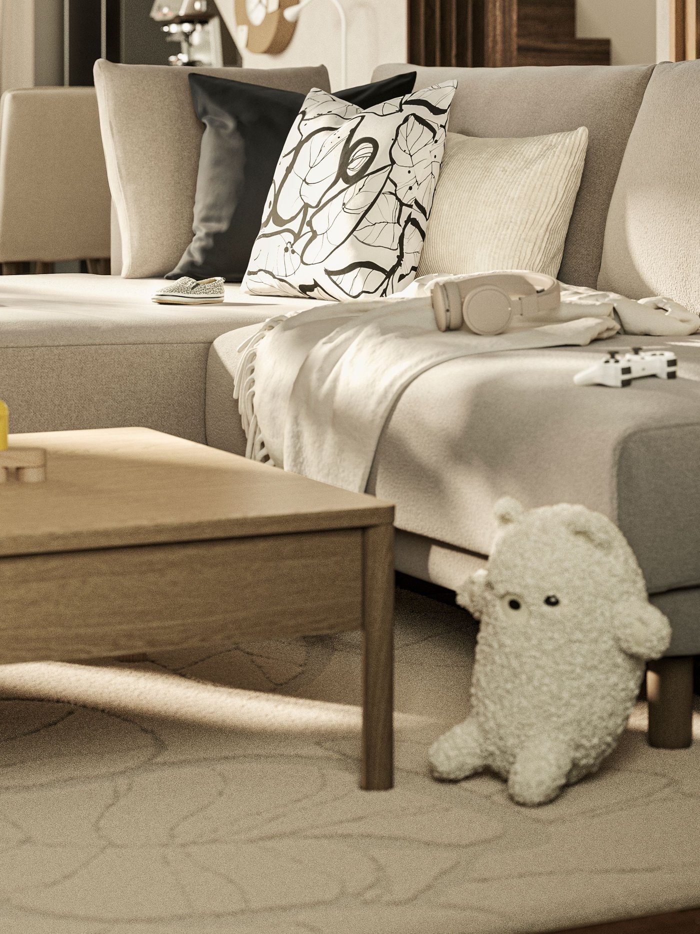 Helles Wohnzimmer mit einem beigen Sofa, Kissen und Decken, davor ein niedriger Holztisch mit Holzspielzeug. Auf dem Teppich liegt ein weisses Kuscheltier, daneben steht ein Regal mit weiteren Spielzeugen.