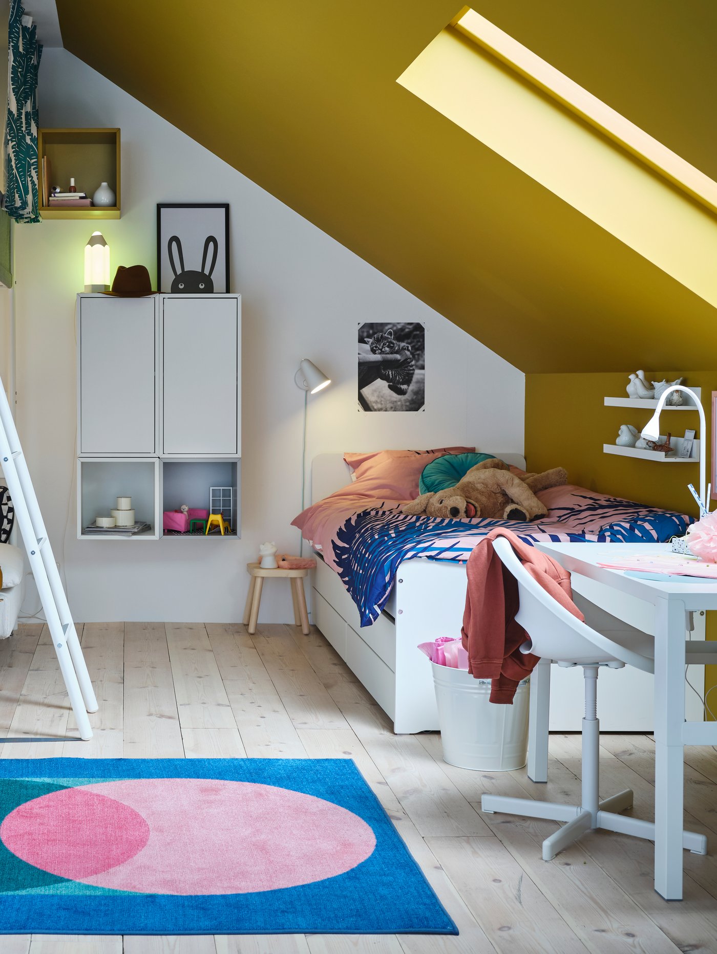 Ein weisses SLÄKT Bett in einem Schlafzimmer mit schrägem, gelbem Dach.