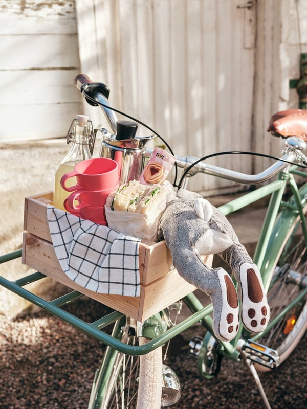 Ett kaningosedjur ligger i en cykelkorg tillsammans med fika.