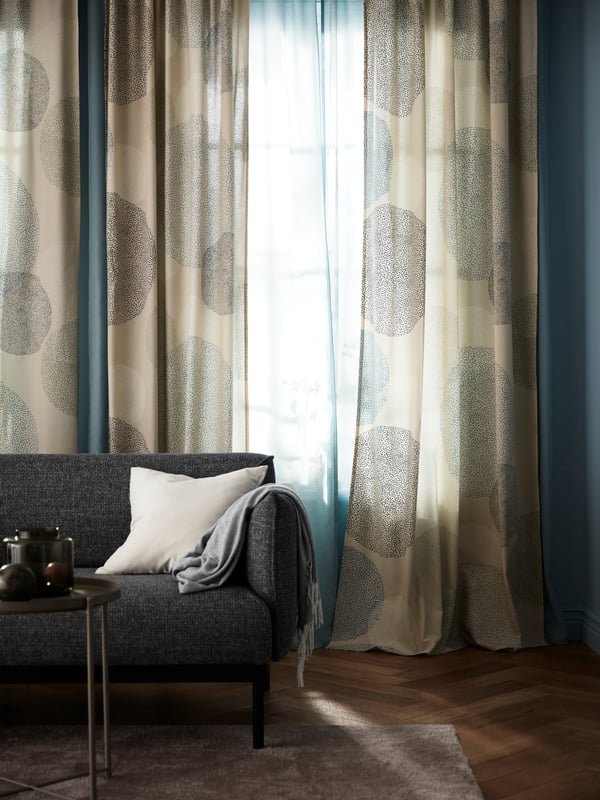 Tenda SANDÄNGSFLY sopra una tenda velata che lascia passare la luce attraverso un salotto con divano.