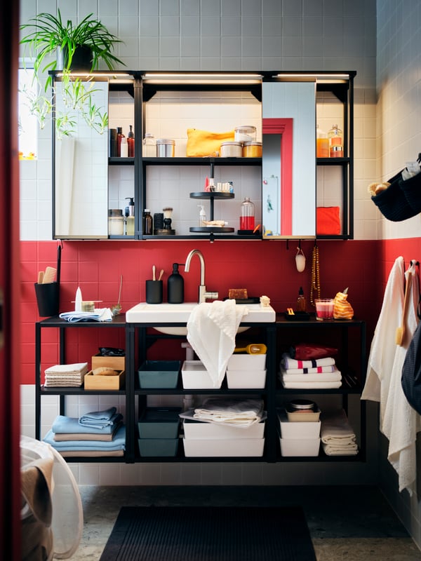 Un cuarto de baño con azulejos rojos y blancos, con una gran combinación ENHET con gabinetes abiertos, llena de accesorios ordenados.