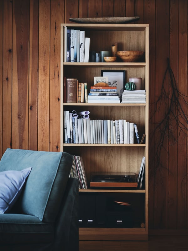 A TONSTAD brown bookcase with various books in it.