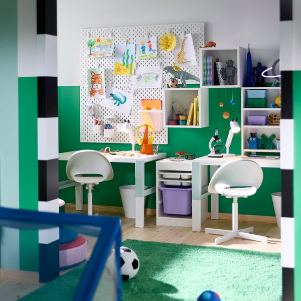 A children’s study area with a PAHL desk and two chairs, with storage boxes and wall organisers holding craft materials.