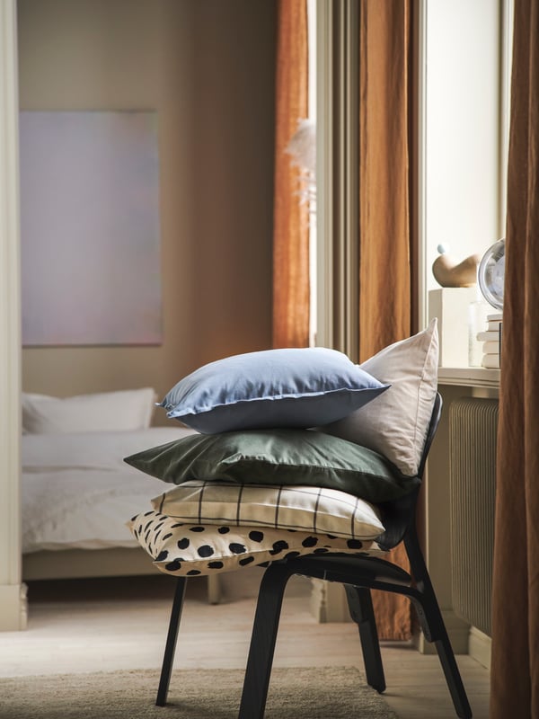 Cushions in different cushion covers including one in a light blue GURLI cushion cover on top of a FRÖSET easy chair.