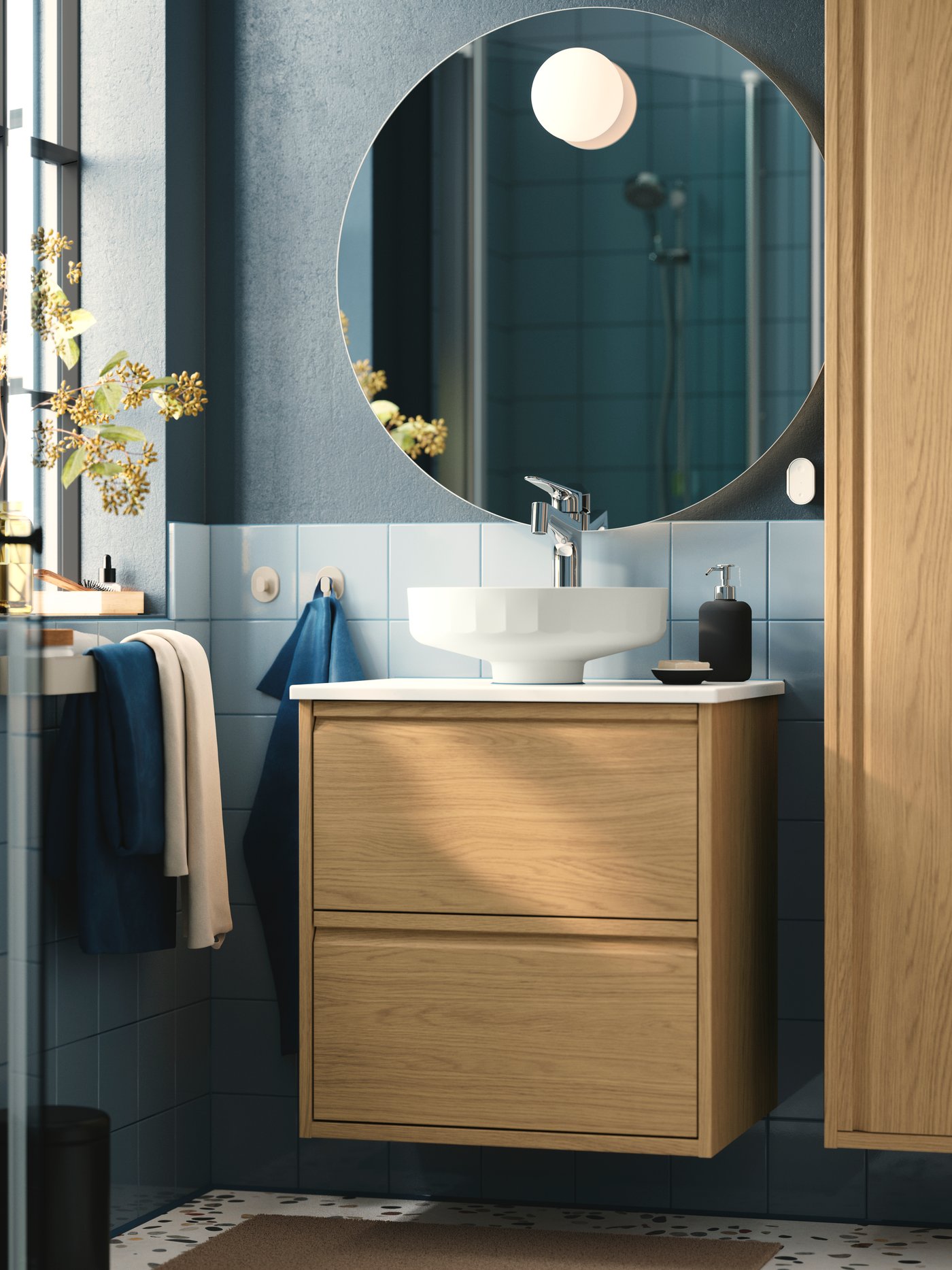 A bathroom featuring a natural colour ÄNGSJÖN vanity unit with two drawers and a round mirror above a sink.