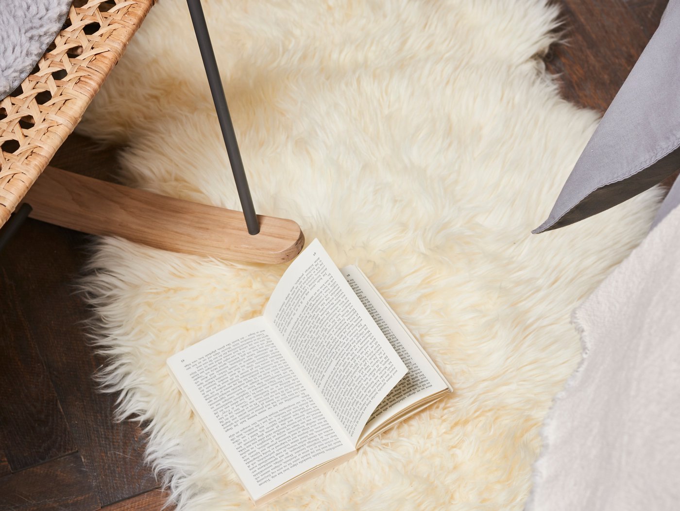 A white ULLERSLEV rug sits on a wood floor. A chair and book rest on top of it. 